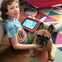 Smiling little girl sitting with a dog during in home boarding